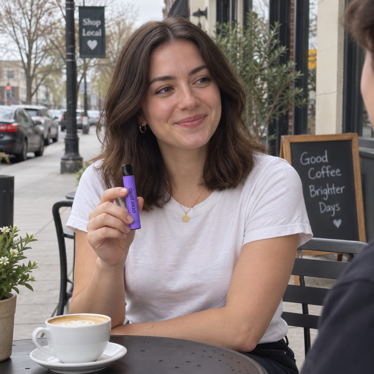 Illustrative scene: Young adult woman holding the purple Grape stick at an outdoor cafe